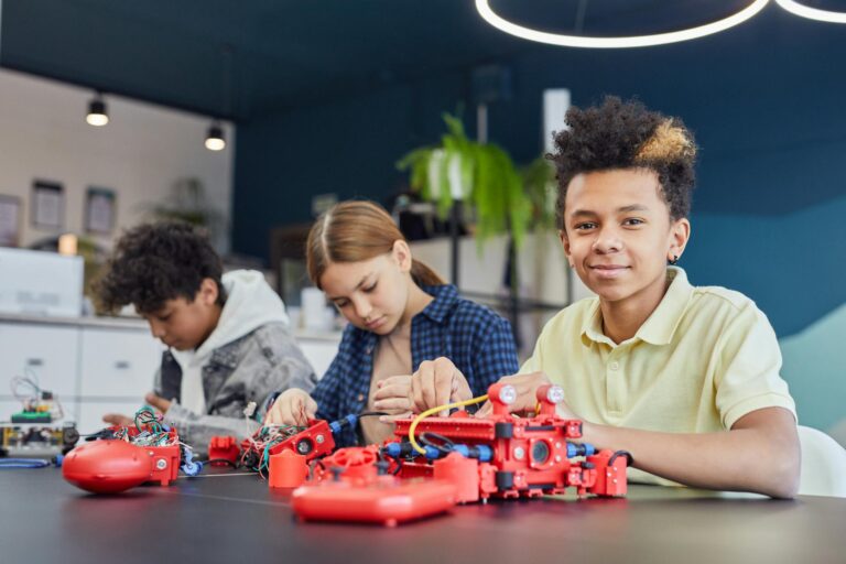 Three kids collaborating on a robotics project in a modern classroom setting.